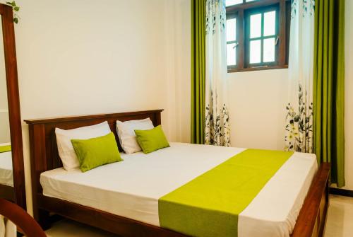 a bedroom with a bed with green pillows and a window at Hidden Pearl in Kandy
