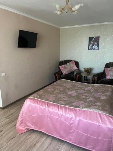 a bedroom with a pink bed and two chairs at Апартаменти на Артилерійській 2 , Центр in Mykolaiv