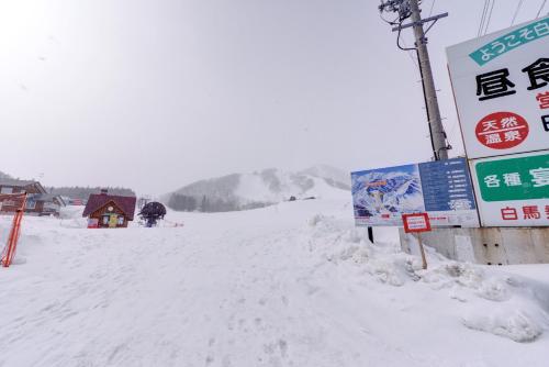 a snow covered road with a sign and a building at Hakuba Alps Hotel in Otari