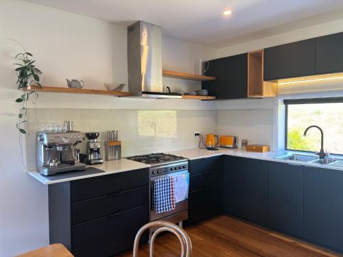 a kitchen with black cabinets and a stove top oven at Girayir Cottage in Federal