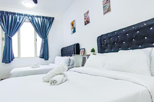 two white beds in a bedroom with blue curtains at Peaceful Luxury at Tresor Klang by HCK in Petaling Jaya