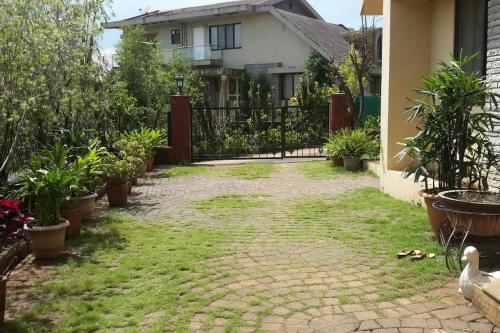 a yard with plants and a fence in front of a house at Garden Villa in Mahabaleshwar