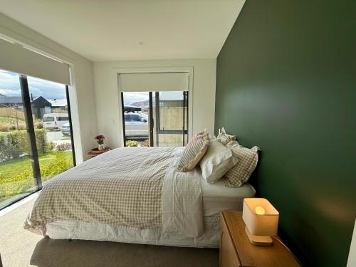 a bedroom with a large bed and a large window at The Green Room in Queenstown Airport