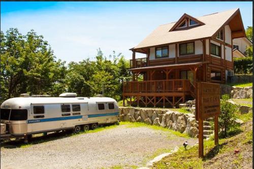 a house with a rv parked in front of it at 大室山の麓ログハウスすくすく in Ito