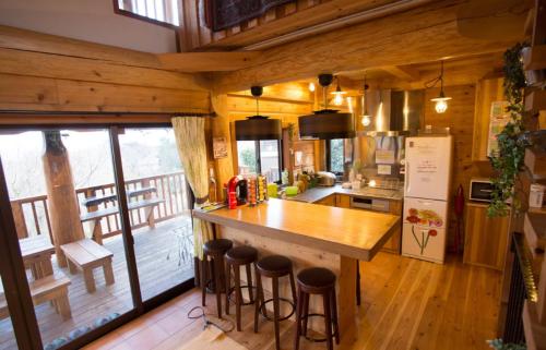 a kitchen with a counter and stools in a cabin at 大室山の麓ログハウスすくすく in Ito