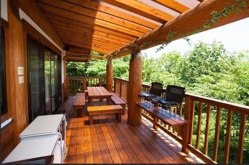 a porch with benches and tables on a wooden deck at 大室山の麓ログハウスすくすく in Ito