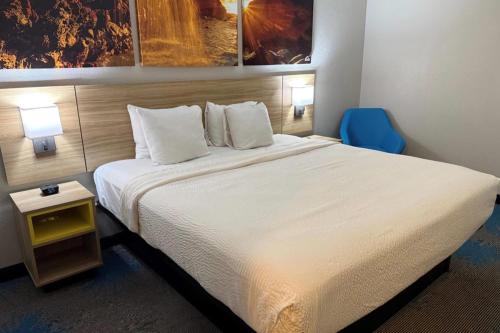 a hotel room with a large bed and a blue chair at Days Inn by Wyndham Canon City in Canon City