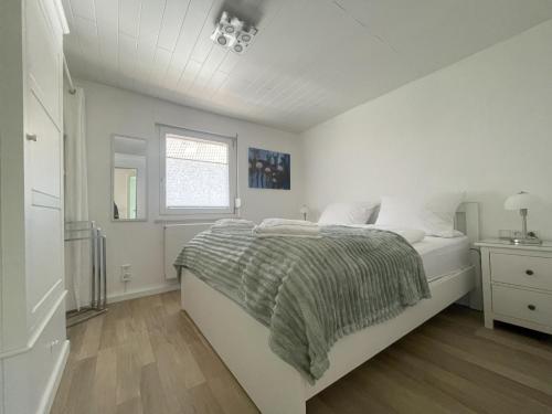 a white bedroom with a bed and a window at Ferienhaus Hirschle | Sauna | Hunde | Zaun in Schömberg