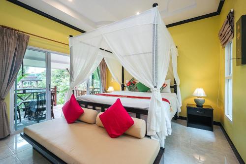 - une chambre avec un lit à baldaquin et des oreillers roses dans l'établissement Thai Modern Resort & Spa "Newly Renovated", à Chalong