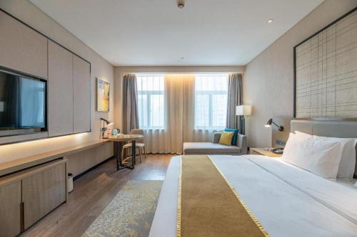 a hotel room with a bed and a flat screen tv at Echarm Hotel Jinan Railway Station Daming Lake in Jinan