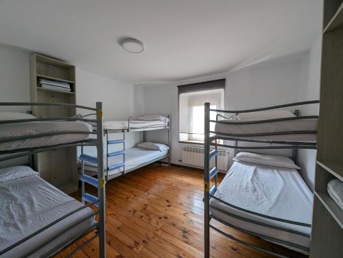 a room with three bunk beds and a window at Albergue El Alfar/Pilgrim Hostel in Hornillos del Camino