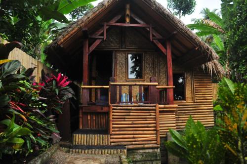 a small wooden house with a balcony in a garden at Green Haven Homestay in Tetebatu