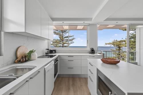 a white kitchen with a view of the ocean at Elegant Beachfront Retreat with Fabulous Views in Sydney