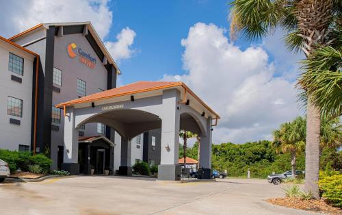 a hotel building with a parking lot and a palm tree at Comfort Suites Oil Center in Lafayette