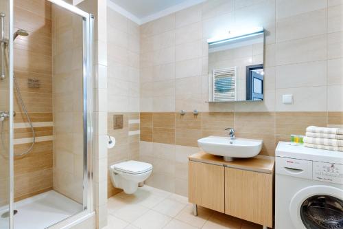 a bathroom with a toilet sink and a washing machine at Apartament Przy Latarni in Kołobrzeg