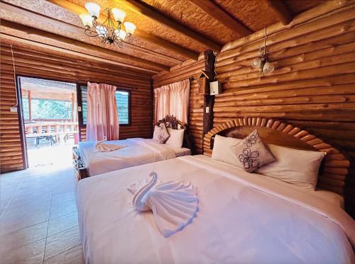 ein Schlafzimmer mit zwei Betten in einer Blockhütte in der Unterkunft ศศิคันทรี รีสอร์ท in Suan Phung