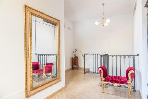 a mirror and two red chairs in a room at B&B Casa Cavour in San Benedetto del Tronto