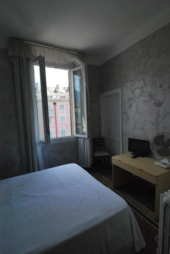 a bedroom with a bed and a desk and a window at Albergo La Vela in Rapallo