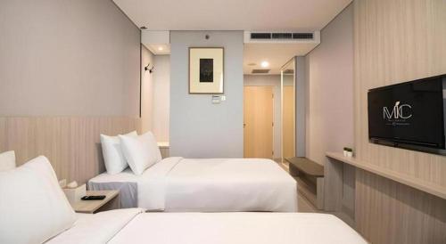 Una habitación de hotel con dos camas y un televisor de pantalla plana. en MIC Residence, en Yogyakarta