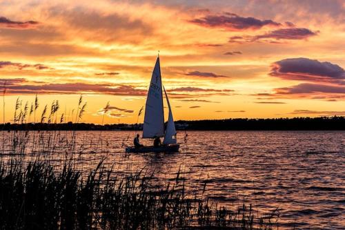 ein Segelboot auf dem Wasser bei Sonnenuntergang in der Unterkunft Holiday home in Markkleeberg near a lake in Markkleeberg