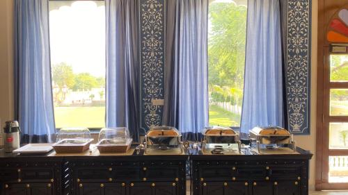 Un buffet con tres cuencos delante de una ventana. en Umrao Mahal - A Boutique Heritage Hotel & Resort Jaipur, en Jaipur