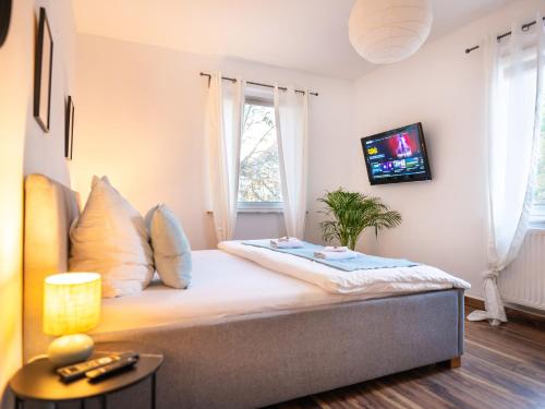 コー​​ブルクにあるGreenTreeHomes - Herzstück Kirsche- im Zentrum Coburgsの壁にテレビが付いたベッドのある寝室