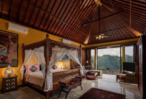 a bedroom with a canopy bed and a living room at Villa Air Terjun Bucuan in Sukawati