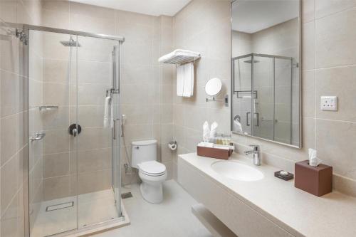 a bathroom with a shower and a toilet and a sink at Landmark Hotels & Suites - Formerly Qamar Hotel in Jeddah