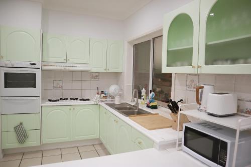 a kitchen with green cabinets and a sink at Double room with shared bathoom in Auburn