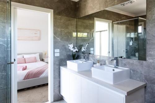 a bathroom with two sinks and a bed and a mirror at Bright, comfortable family home in leafy Forest Hill in Forest Hill