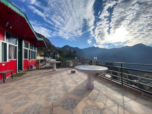 un patio con mesa y vistas a las montañas en hotel first view, en Chopta
