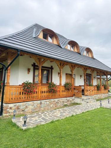 une grande maison avec un toit en gambrel dans l'établissement Casa Moroșanului Vișeu de Sus, à Vişeu de Sus
