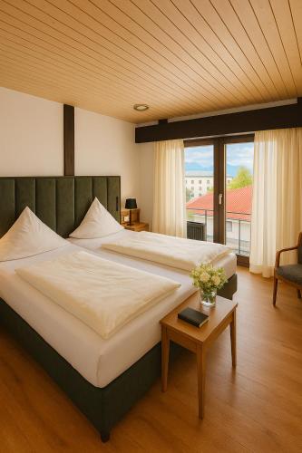 ein Schlafzimmer mit einem großen Bett und einem Tisch in der Unterkunft Hotel Paffhausen in Wirges