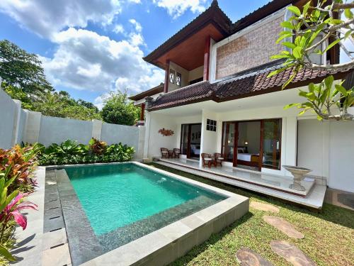 a villa with a swimming pool in front of a house at ASAnA Guesthouse in Ubud