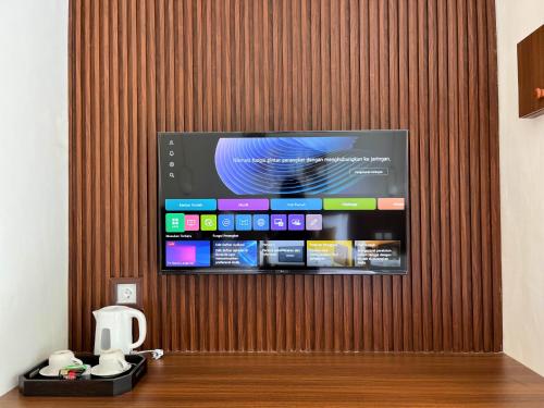 a flat screen tv hanging on a wooden wall at ASAnA Guesthouse in Ubud