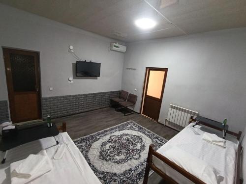 a room with two beds and a television on the wall at Caravan Hostel in Tashkent International Airport