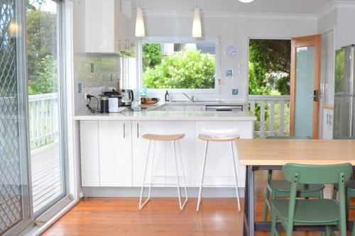a kitchen with a wooden table and stools in it at Classic Meets Contemporary 1960's Beach House in Malua Bay