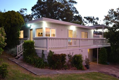 a small white house with a large deck at Classic Meets Contemporary 1960's Beach House in Malua Bay