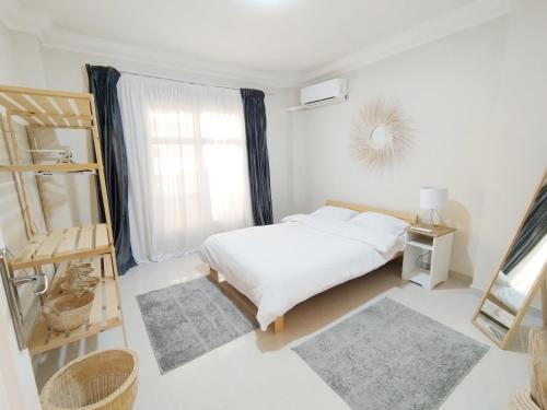 a white bedroom with a bed and a window at white Bear in Madinaty