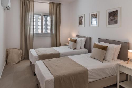 two beds in a hotel room with white walls at Avyra Residences Chrysakama Sea View in Polis Chrysochous
