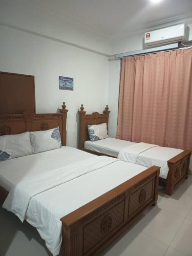 a bedroom with two beds and a window at Hotel Nusantara in Jertih