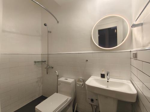 a bathroom with a toilet and a sink and a mirror at Voss Condominium in Manila