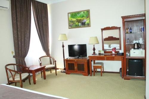 a hotel room with a bed and a desk and a television at Firuz Hotel in Khujand
