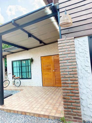 a house with a wooden door and a bike on a patio at BaanBaimai Homestay in Chiang Rai