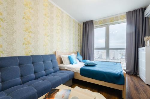 a bedroom with a bed and a blue couch at Panoramic view Lebedinny flat in Kyiv
