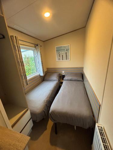 a small room with two beds and a window at Meadow Banks Combe Haven in Hastings