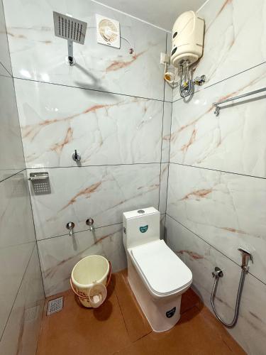 a bathroom with a white toilet and a shower at Sathya HS-2 Bedroom Family Apartments with Balcony in Guruvāyūr