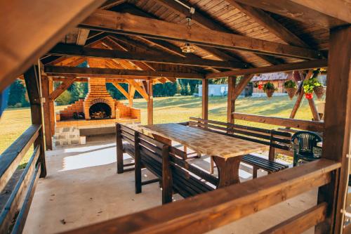a wooden table and benches in a pavilion with a fireplace at Bükkfői vendégház in Borzont