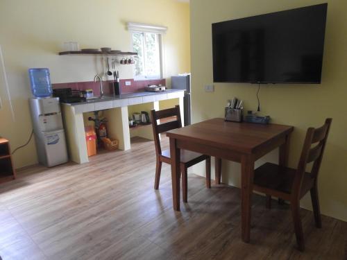 a dining room with a table and a television on a wall at Dom's Oase in Bolod