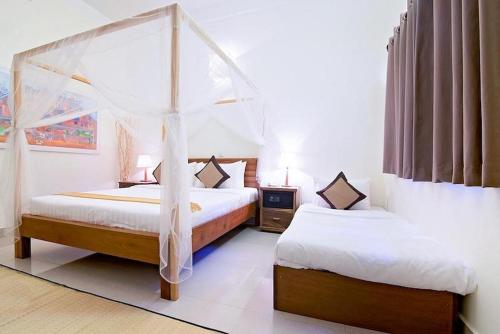 a bedroom with two beds and a canopy bed at La Fontaine de Tara in Siem Reap